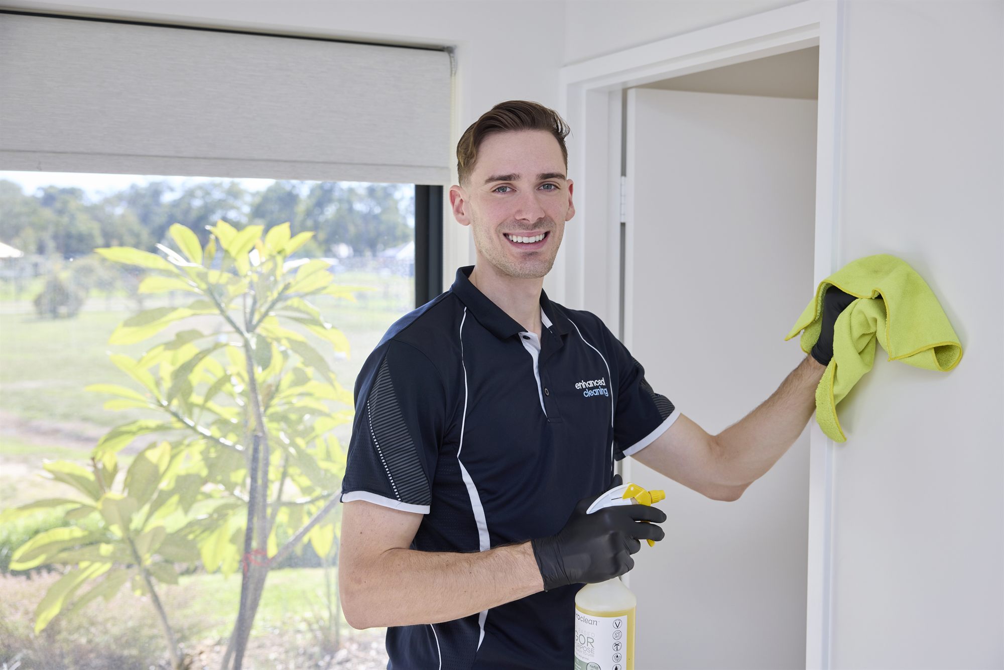 Enhanced Cleaning team member wiping down walls in an empty rental property