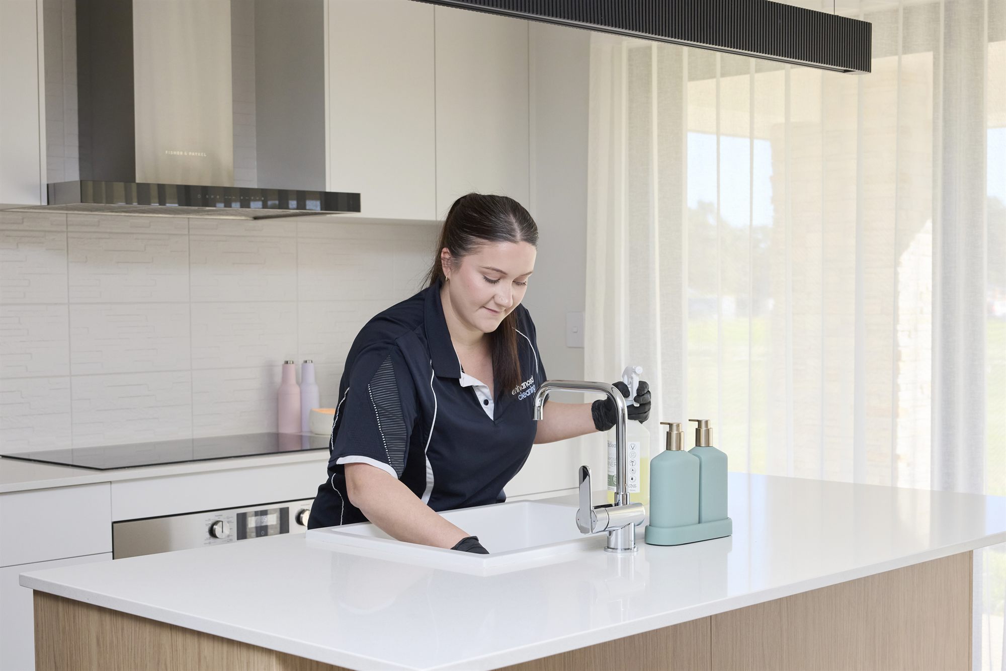 Enhanced Cleaning team member cleaning a kitchen sink with eco-friendly products
